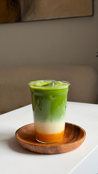 Mango Matcha Latte mit gelber Mangoschicht, Milch und grünem Matcha im Glas