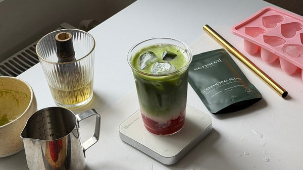 Strawberry Iced Matcha Latte mit drei Schichten neben dem Sensual Matcha Ceremonial Blend Doypack
